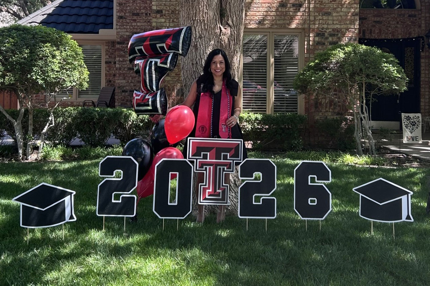 Lesley poses in her front yard with a large card display.