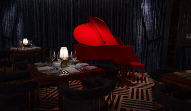 A red piano in a upscale dining room.