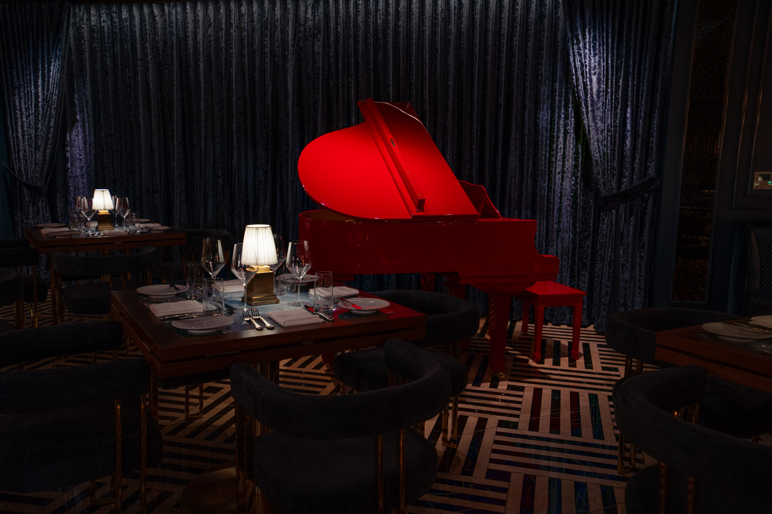 A red piano in a upscale dining room.