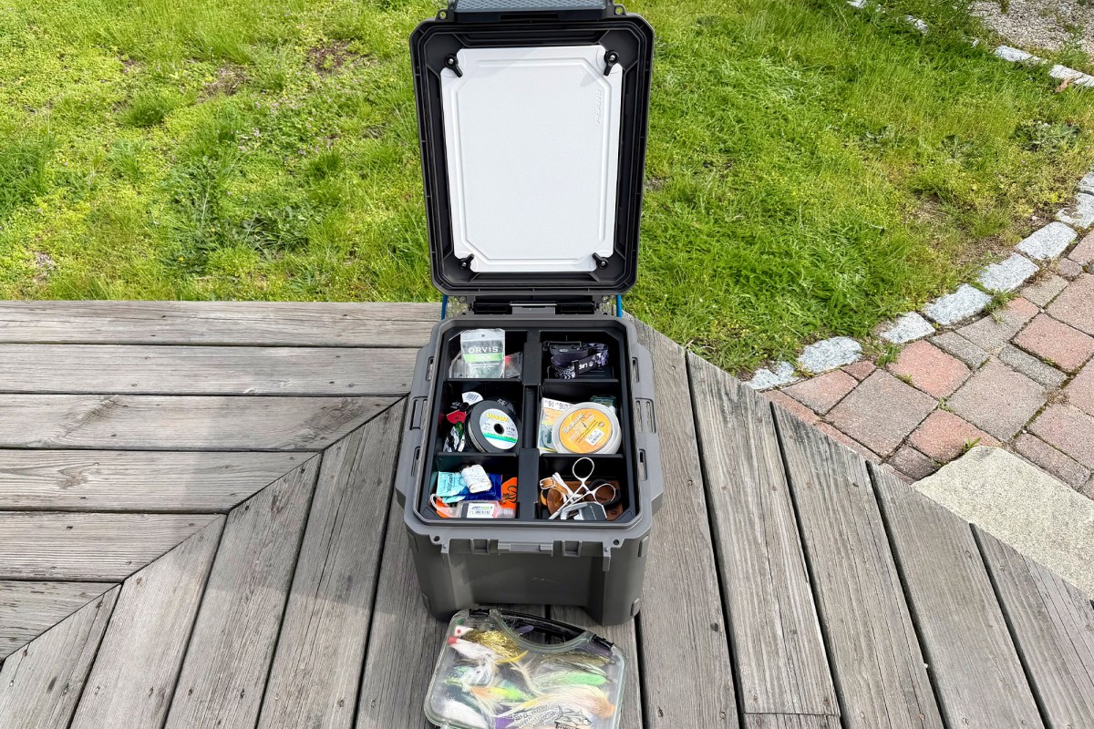 Open Plano box filled with fly fishing gear on a wooden deck