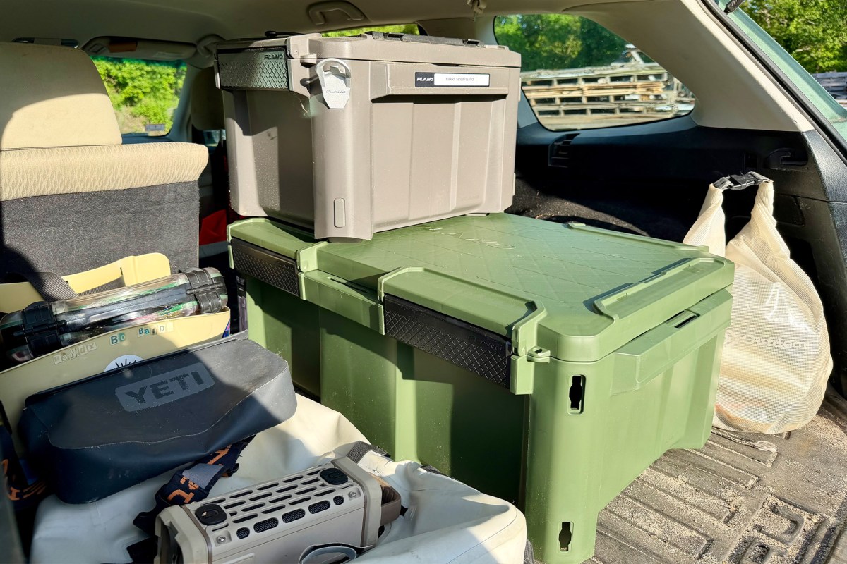 Gray and green storage boxes packed with fishing gear in an SUV trunk