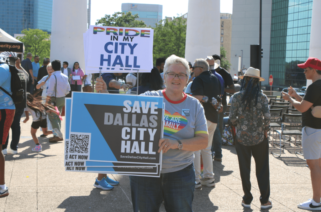 Women displays 'Pride in City Hall' sign at Dallas Flag Raising.