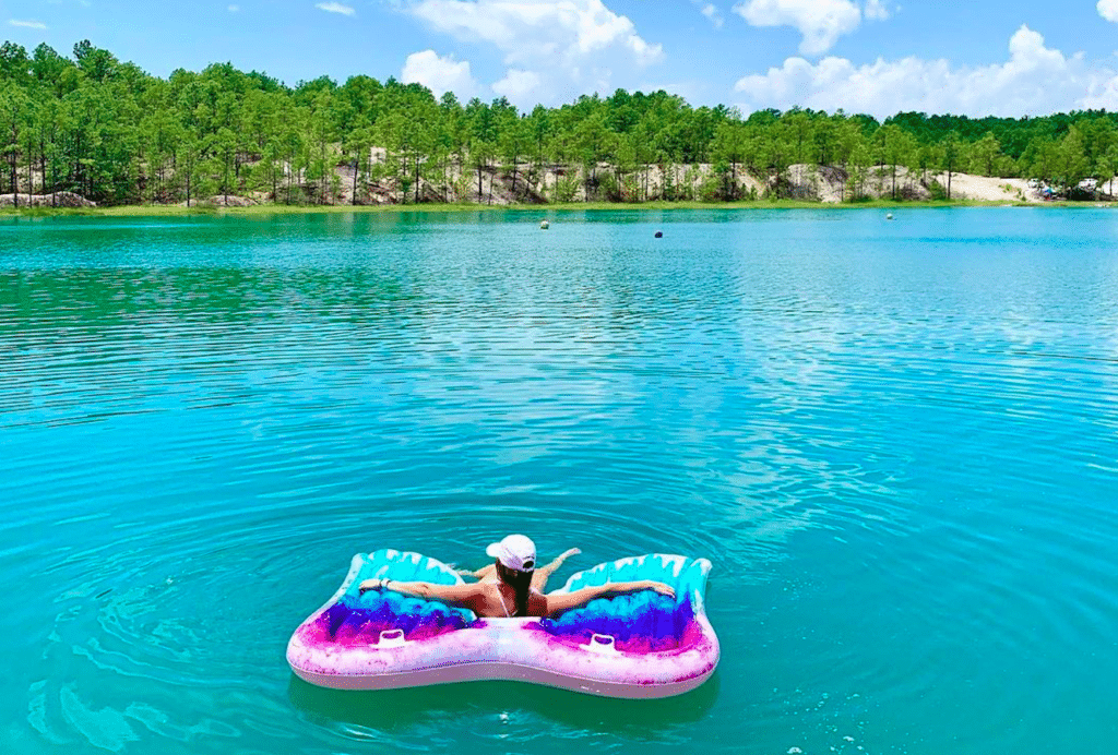 Image shows a woman floating on a clear body of water at the Blue Lagoon in Huntsville outside of Houston. 