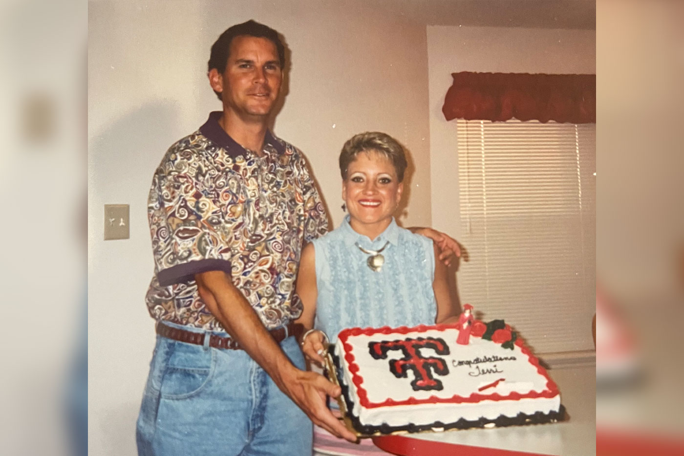 Terri with her husband holding a graduation cake