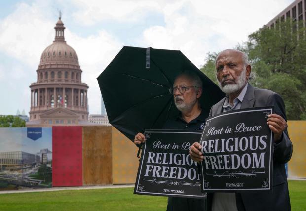 Mohammed Nasrullah, left, and Aziz Soomro, both of Houston, participate in an interfaith funeral-themed protest outside the Barbara Jordan Building in Austin on Monday, June 22, 2026. (Jay Janner/Austin American-Statesman via AP)