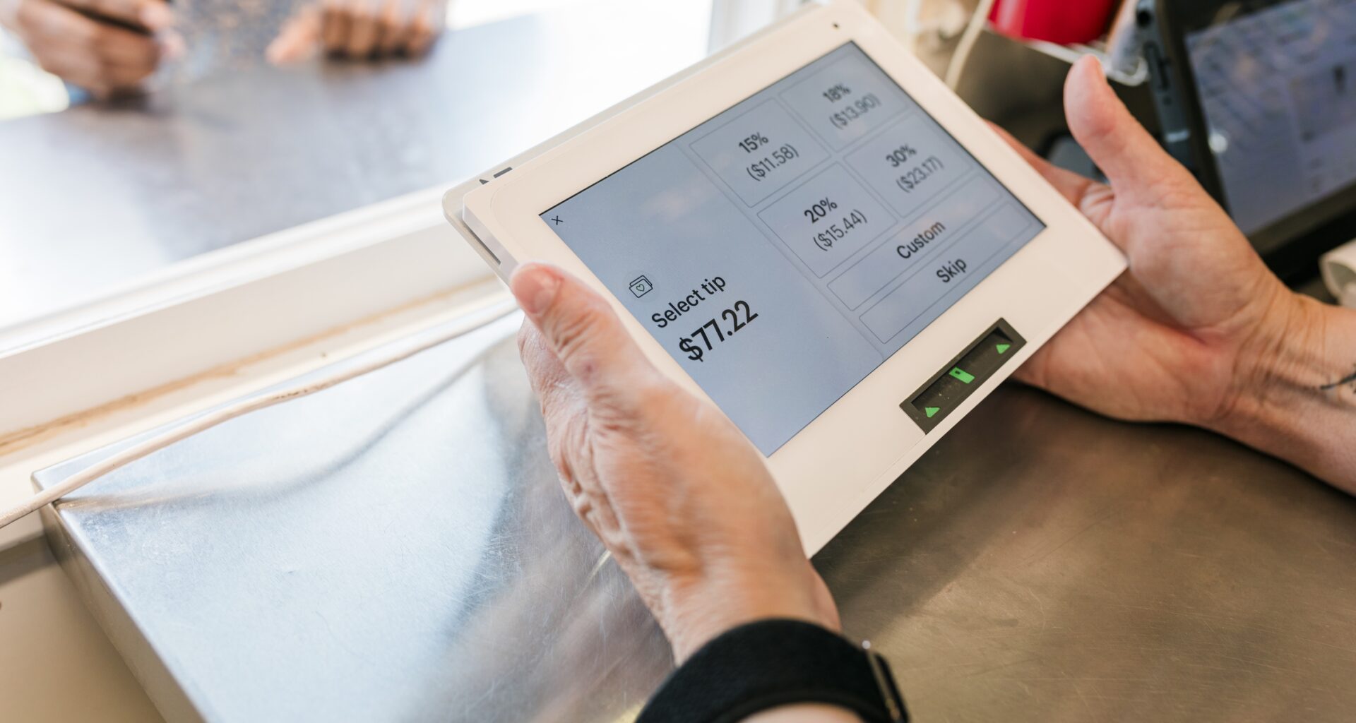 A close-up view of a transaction at the "Hogs and Hops" BBQ event, showcasing the modern payment process. The payment screen displays tipping options while a customer interacts with the staff. The image emphasizes the blend of technology and customer service, reflecting the seamless and efficient transaction experience at the event.