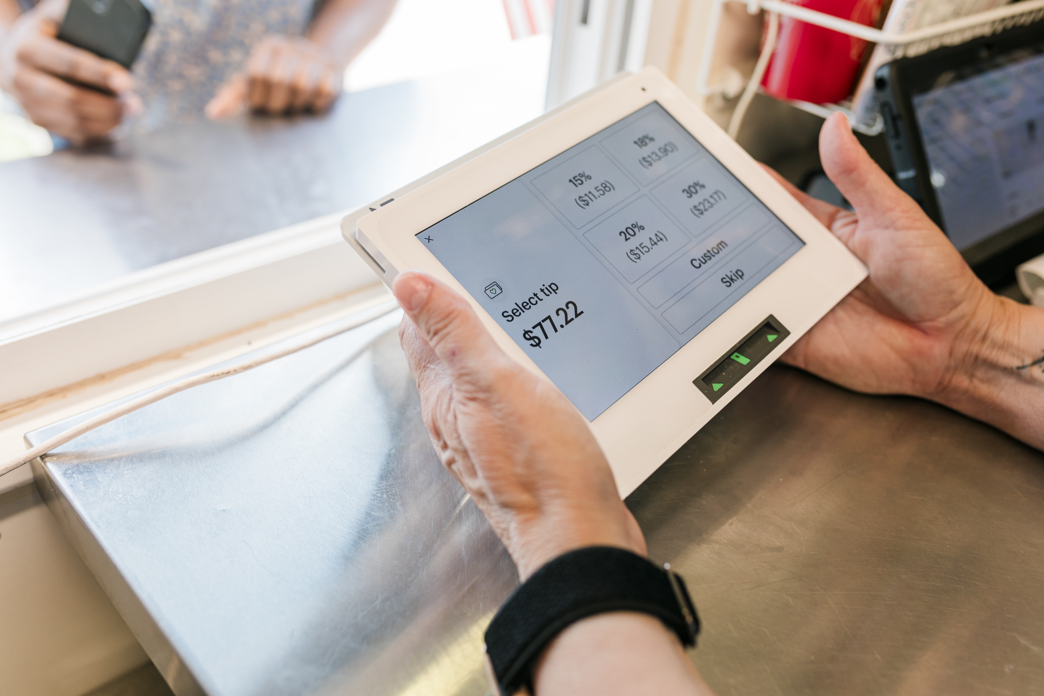 A close-up view of a transaction at the "Hogs and Hops" BBQ event, showcasing the modern payment process. The payment screen displays tipping options while a customer interacts with the staff. The image emphasizes the blend of technology and customer service, reflecting the seamless and efficient transaction experience at the event.