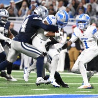 Dec 4, 2025; Detroit, Michigan, USA; Detroit Lions running back Jahmyr Gibbs (0) scores a touchdown against Dallas Cowboys safety Markquese Bell (14) and safety Donovan Wilson (6) during the second half at Ford Field.