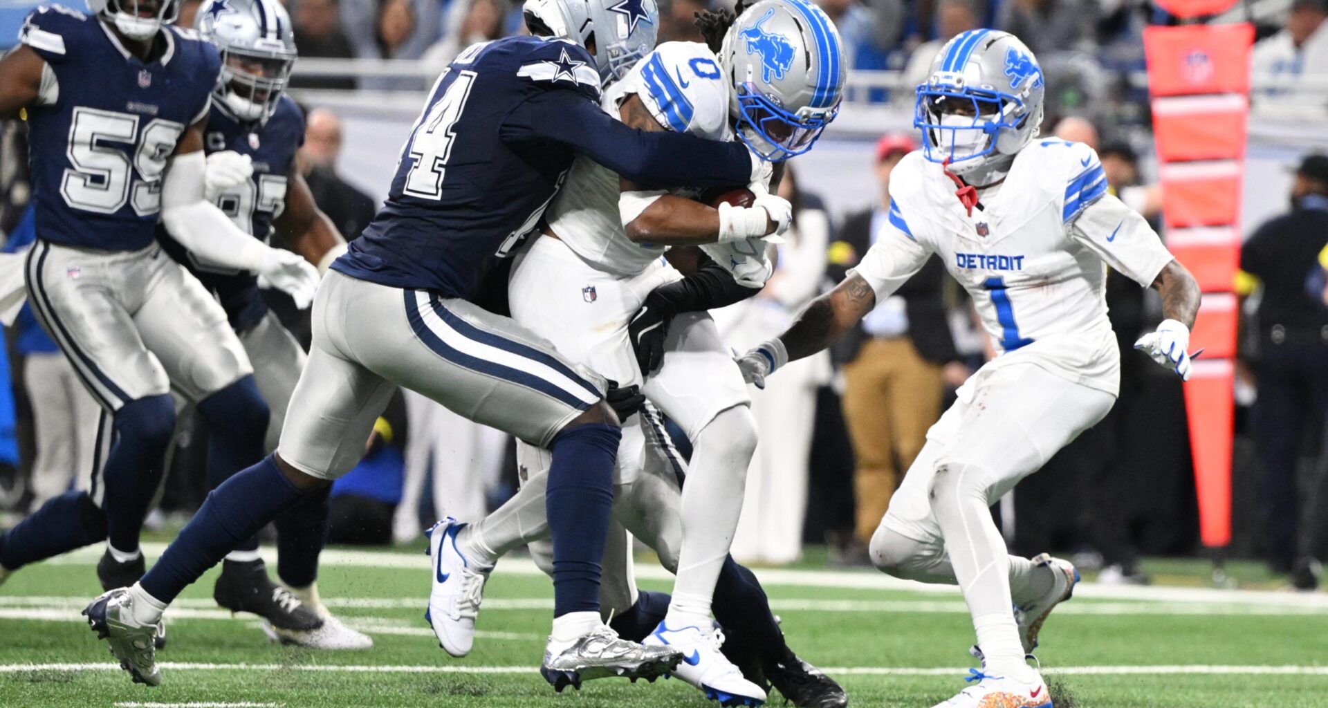 Dec 4, 2025; Detroit, Michigan, USA; Detroit Lions running back Jahmyr Gibbs (0) scores a touchdown against Dallas Cowboys safety Markquese Bell (14) and safety Donovan Wilson (6) during the second half at Ford Field.