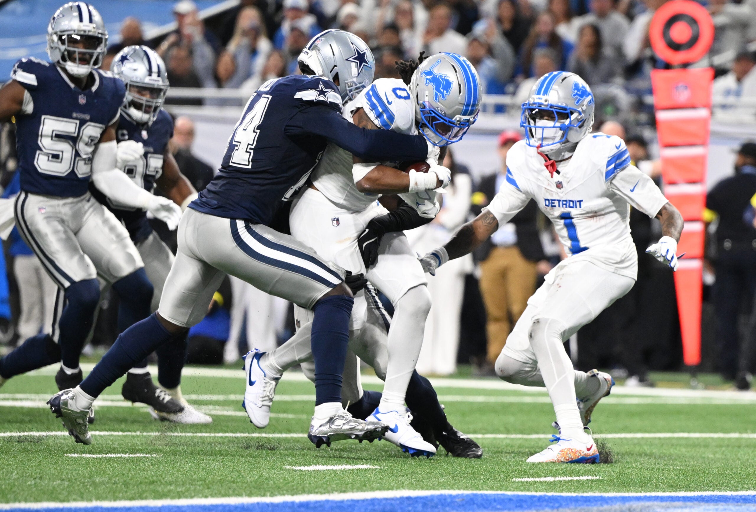 Dec 4, 2025; Detroit, Michigan, USA; Detroit Lions running back Jahmyr Gibbs (0) scores a touchdown against Dallas Cowboys safety Markquese Bell (14) and safety Donovan Wilson (6) during the second half at Ford Field.