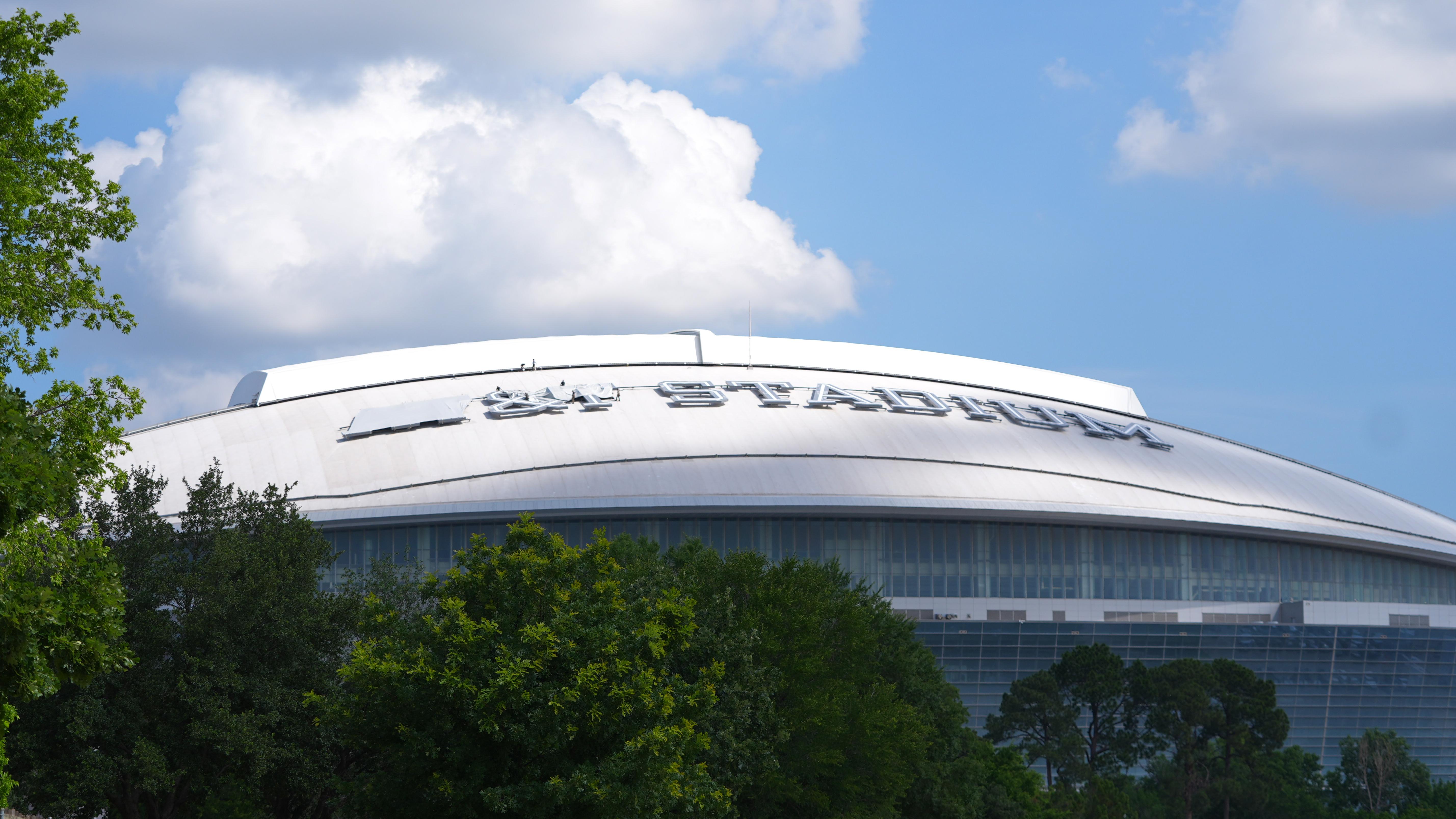 Workers cover signage on the exterior of AT&T Stadium, which...