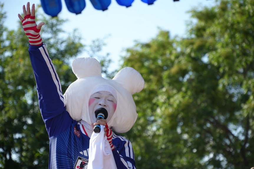A man with a painted white face and a wraparound headdress of bunny ears.