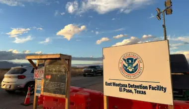 Entrance to Camp East Montana in El Paso, Texas. Image show a white DHS sign and orange barricades on the ground.