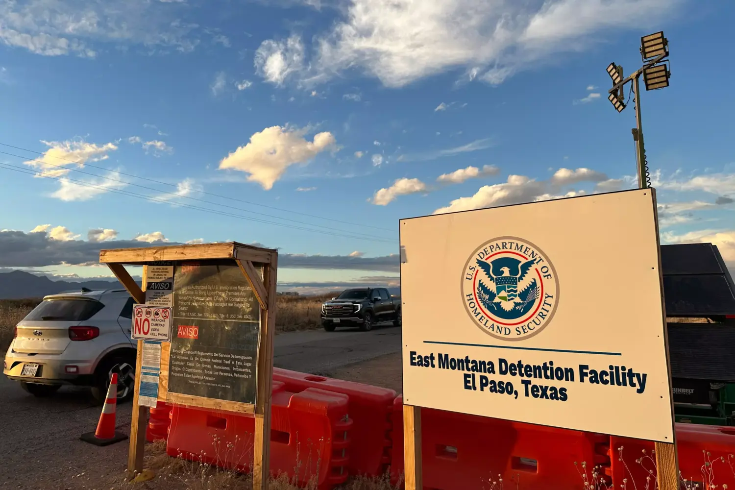 Entrance to Camp East Montana in El Paso, Texas. Image show a white DHS sign and orange barricades on the ground.