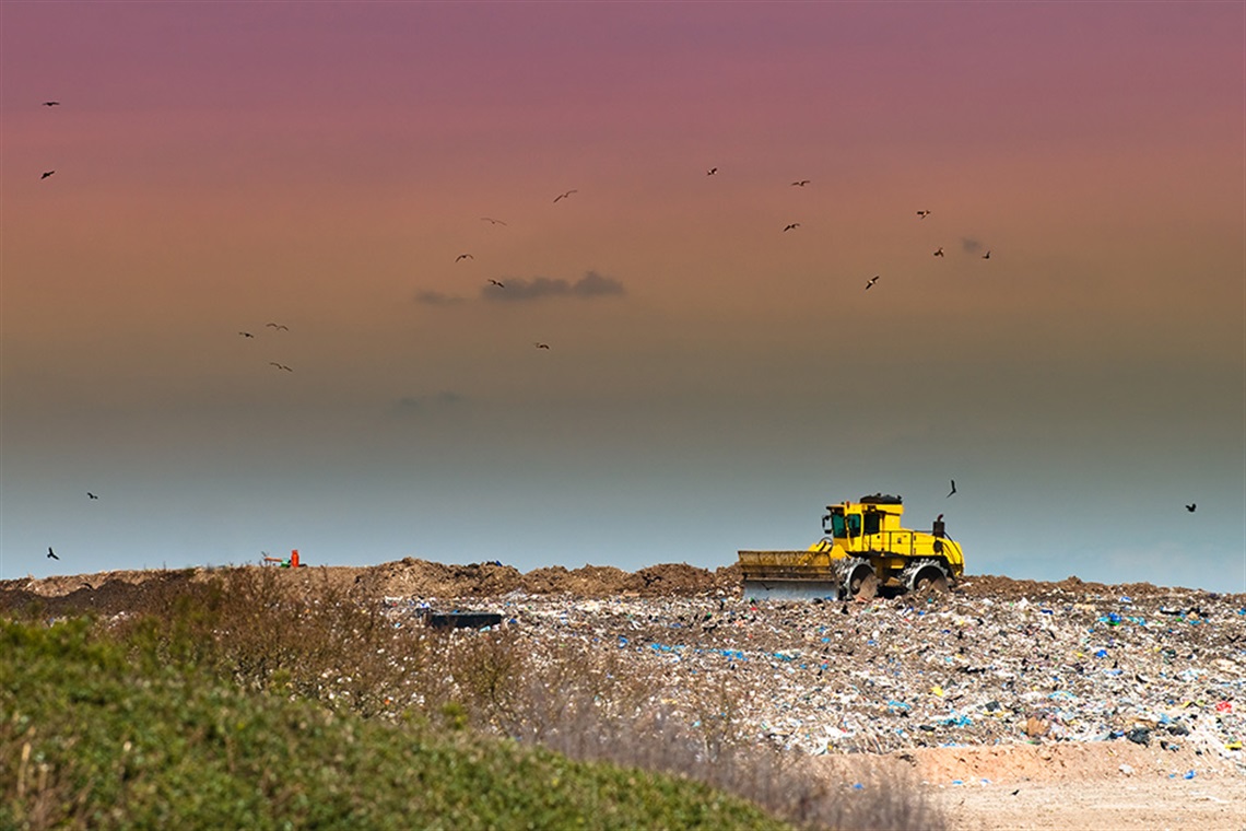 Machinery pushing trash into landfill. 