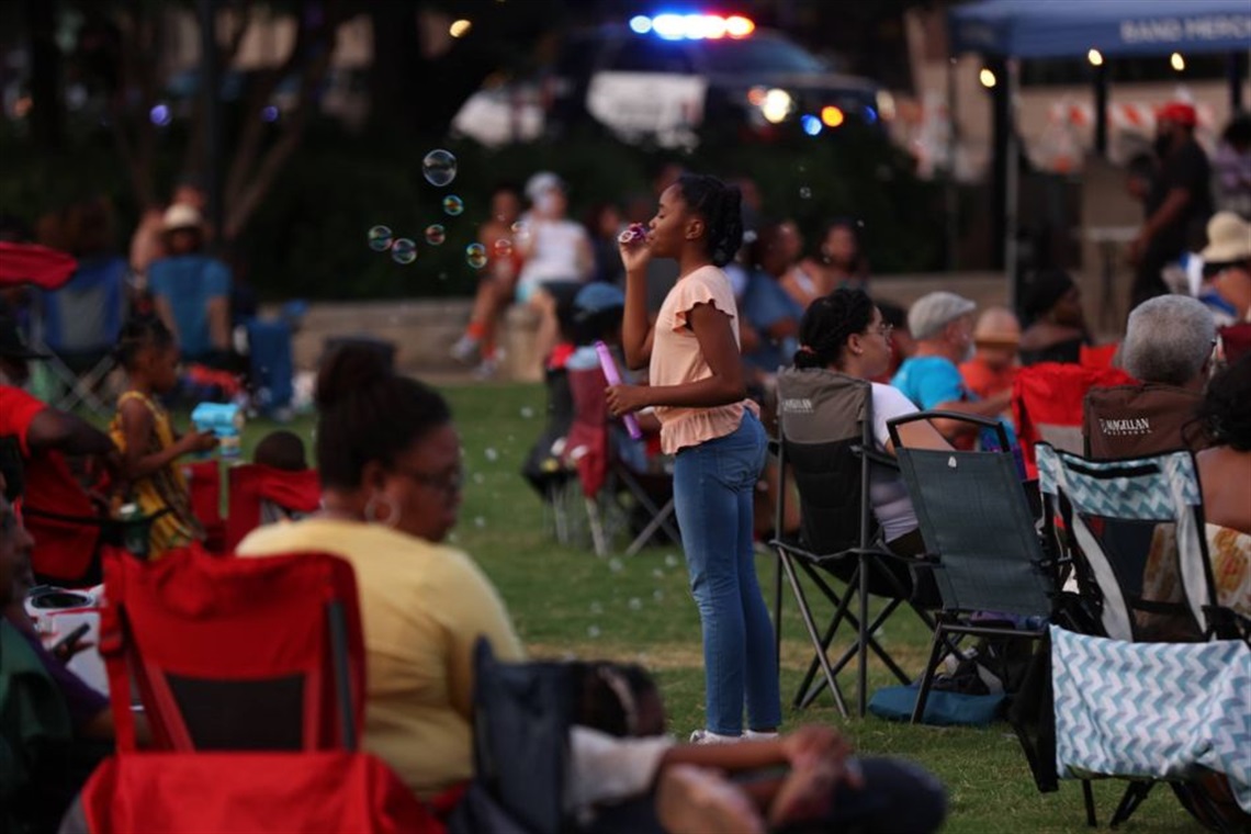 Girl blowing bubbles on the lawn at Levitt Pavilion Arlington surrounded by a crowd