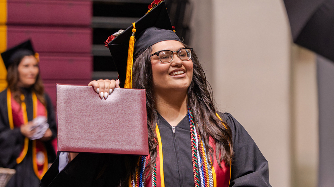 Ashley Caraway holds up her diploma after earning her degree from the McCoy College of Science, Mathematics & Engineering