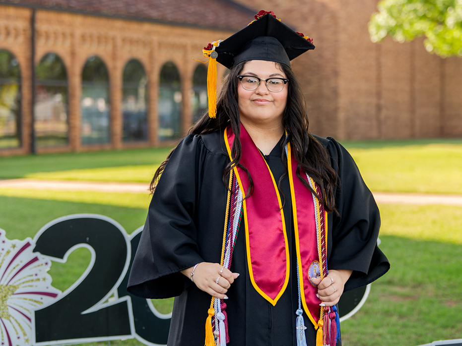 Ashley Caraway stands on graduation day outside of D.L. Ligon Coliseum