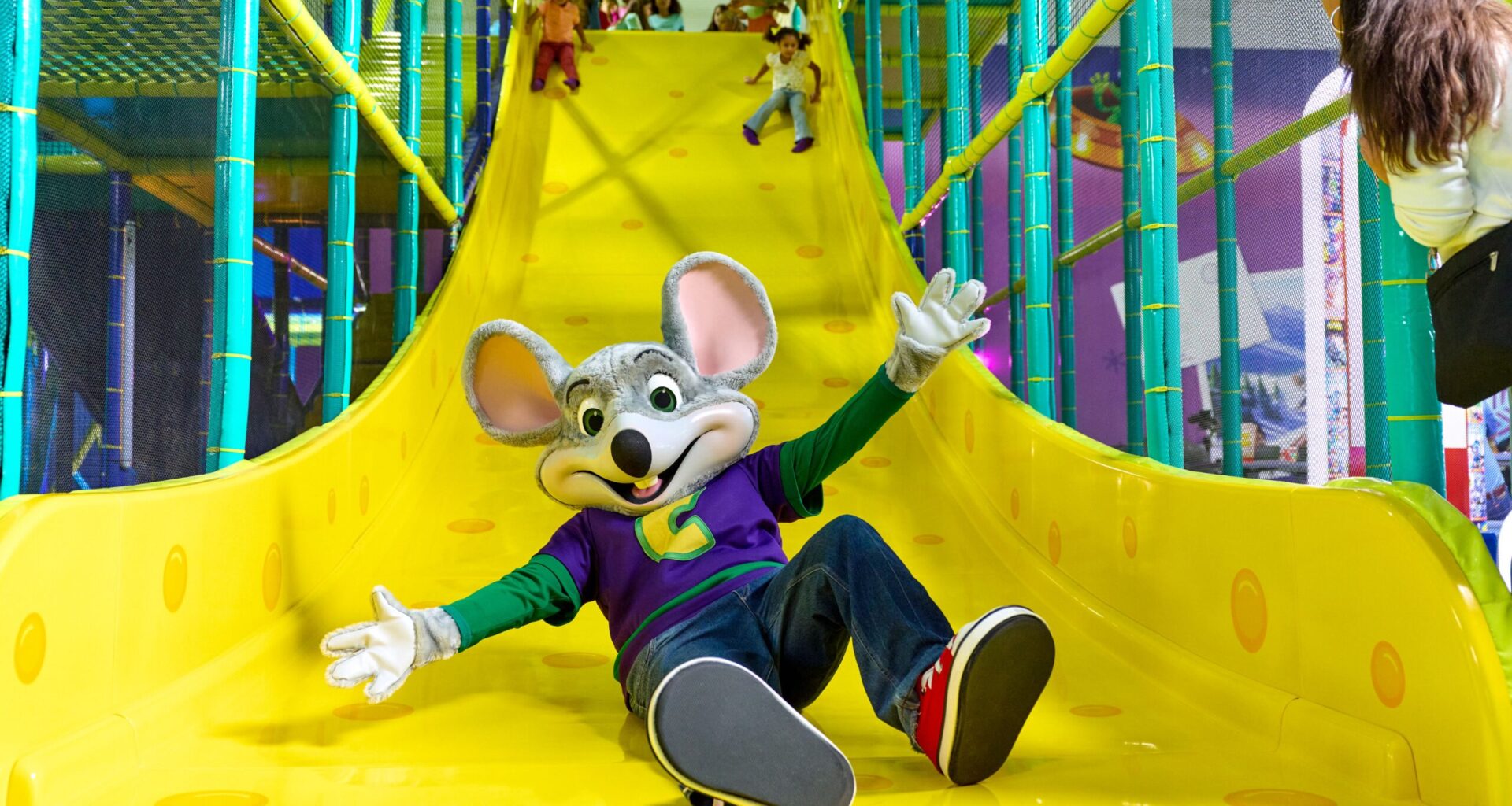 Child-friendly indoor playground with a colorful slide and a cheerful mouse mascot