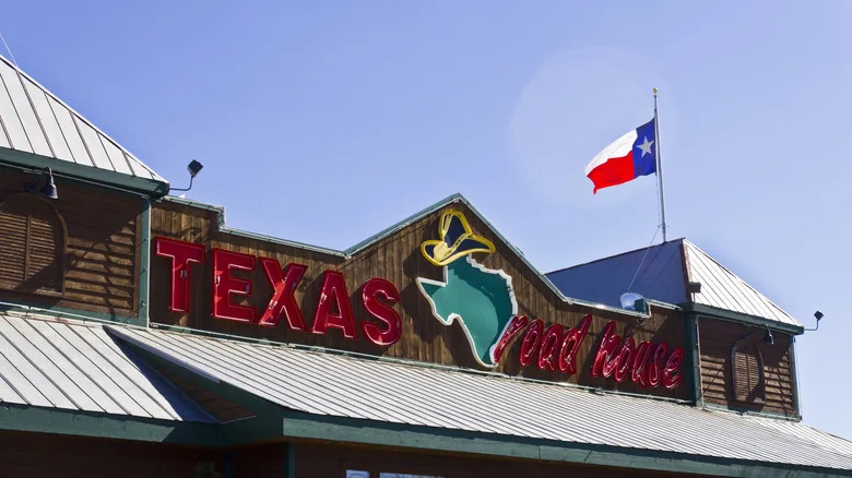 A Texas Roadhouse sign on a restaurant location with Texas flag