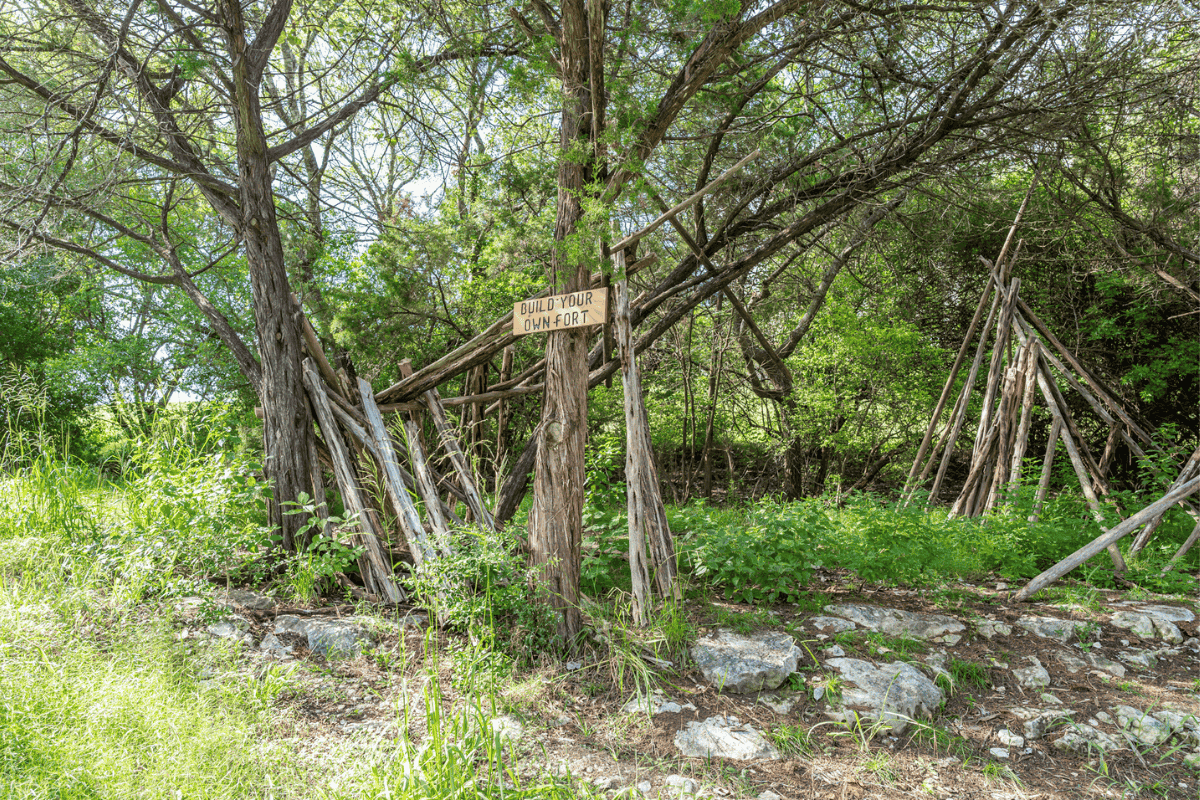 A wooded area with a sign that reads "BUILD YOUR OWN FORT"