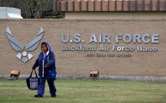 A pedestrian passes the main gate at Lackland Air Force Base in San Antonio. A flu outbreak at the base has sickened nearly 160 troops.