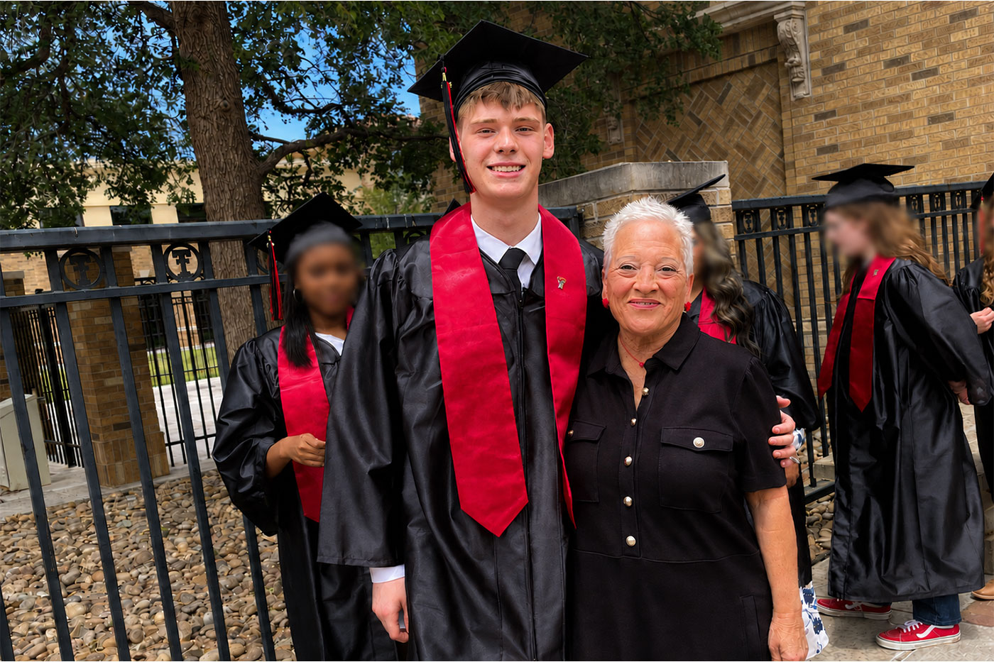 Carter in graduation regalia standing next to Terri. 