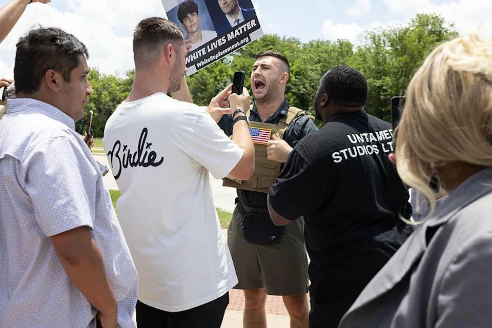 Far-right influencer Jake Lang holds a sign that reads 