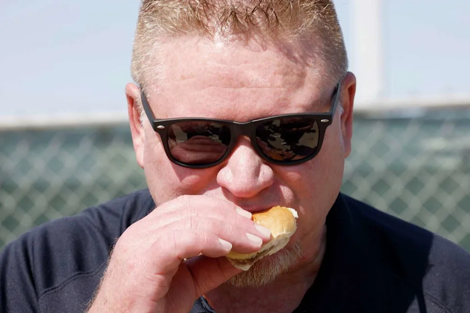 Brian Wade, City of The Colony Council member, eats a White Castle Slider at the groundbreaking on June 2, 2026. (Chitose Suzuki/The Dallas Morning News)