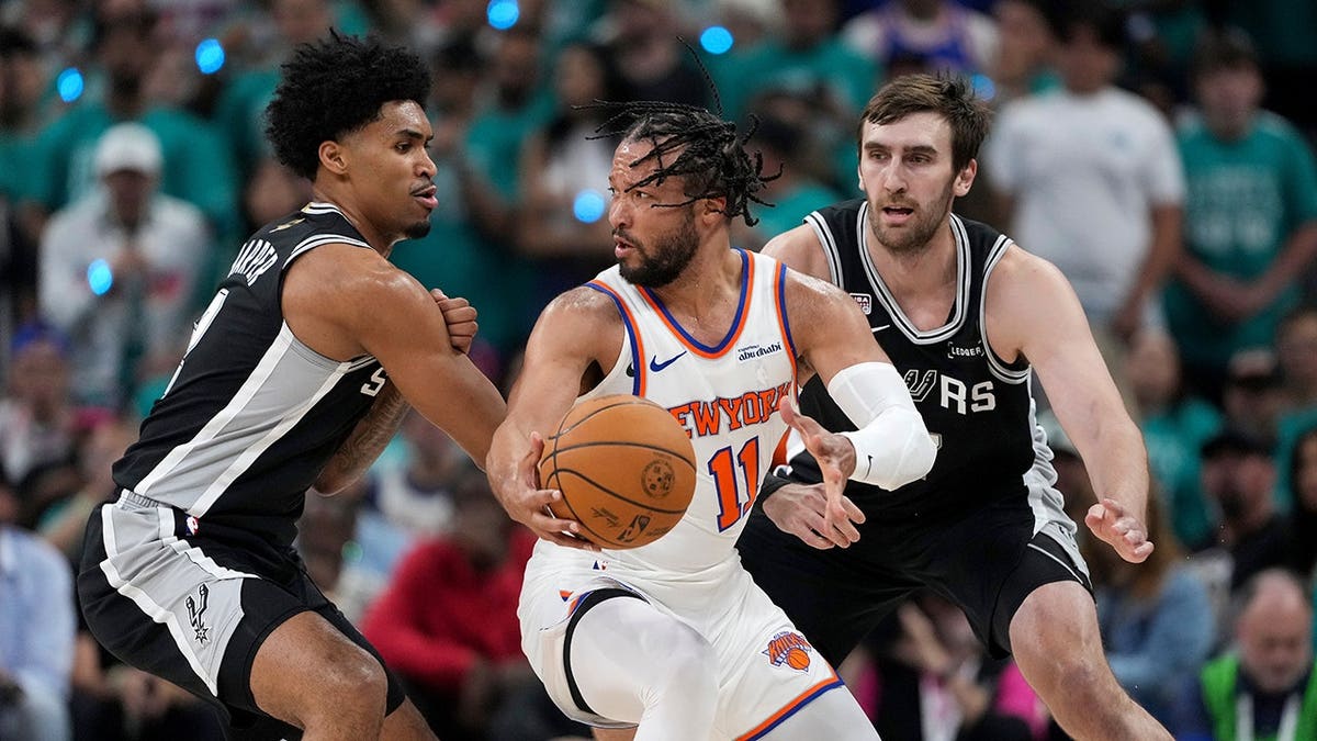 New York Knicks guard Jalen Brunson spinning with basketball as San Antonio Spurs guard Dylan Harper defends