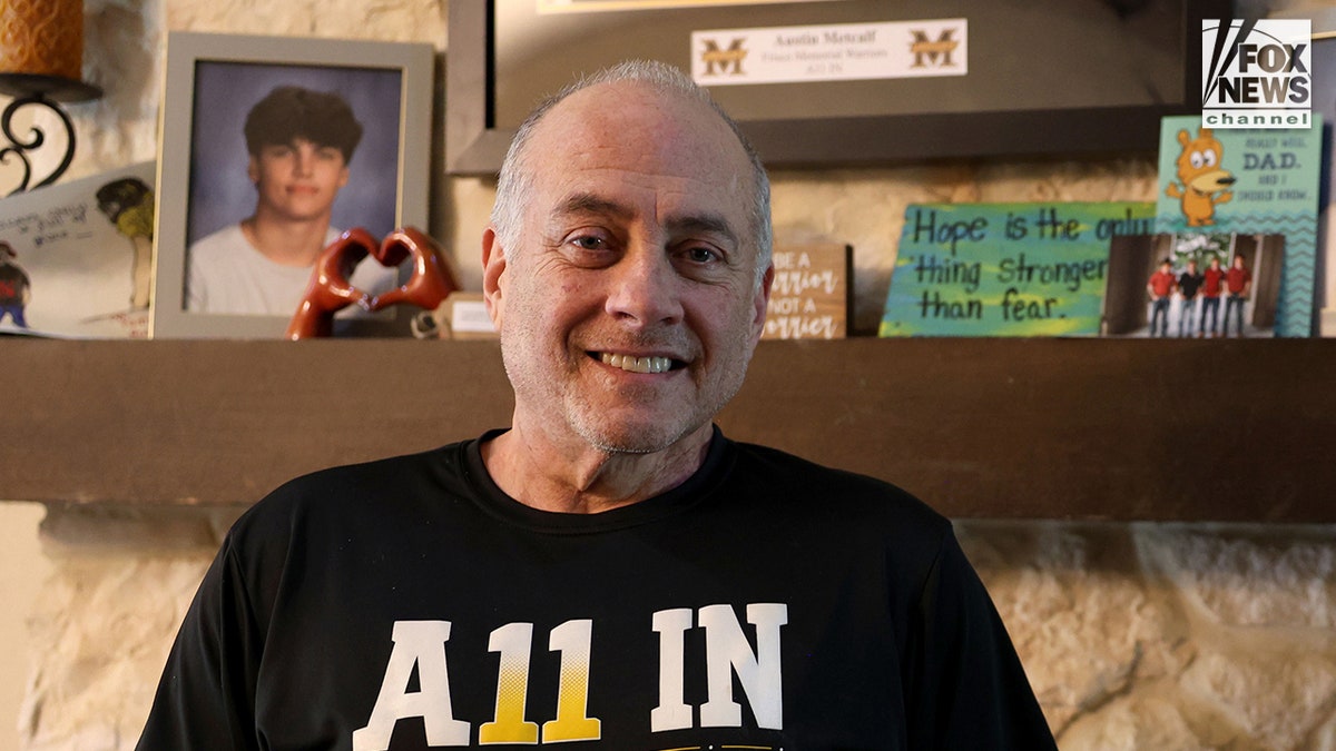 Jeff Metcalf posing with photos of his son Austin Metcalf inside his home during an interview.