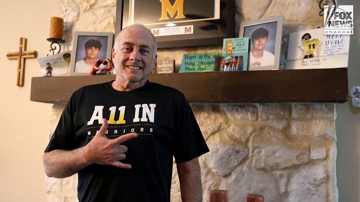 Jeff Metcalf posing with photos of his son Austin Metcalf inside his home during an interview.