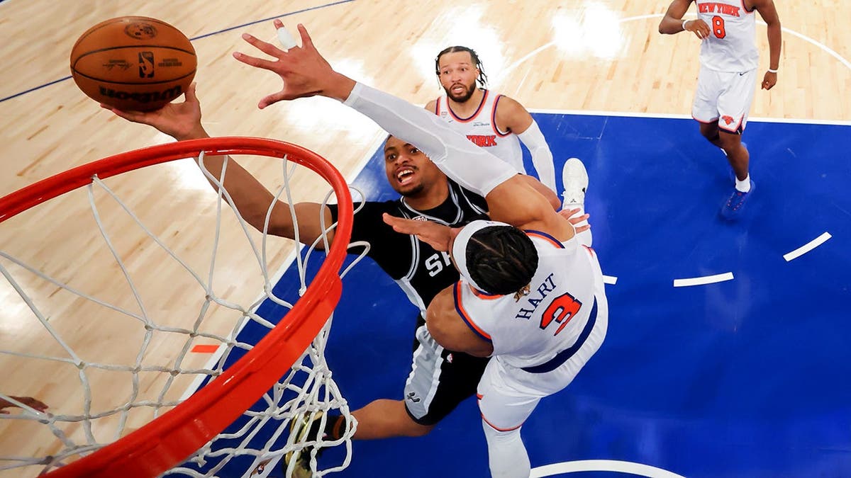 San Antonio Spurs forward Keldon Johnson shooting as New York Knicks guard Josh Hart defends in basketball game