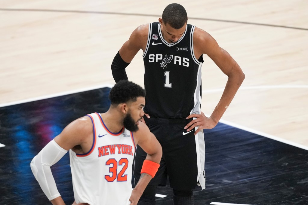 Victor Wembanyama looks down as Karl-Anthony Towns looks towards his bench during the NBA Finals.
