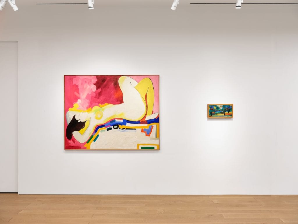 Gallery wall displaying large reclining nude painting beside smaller colorful landscape artwork.