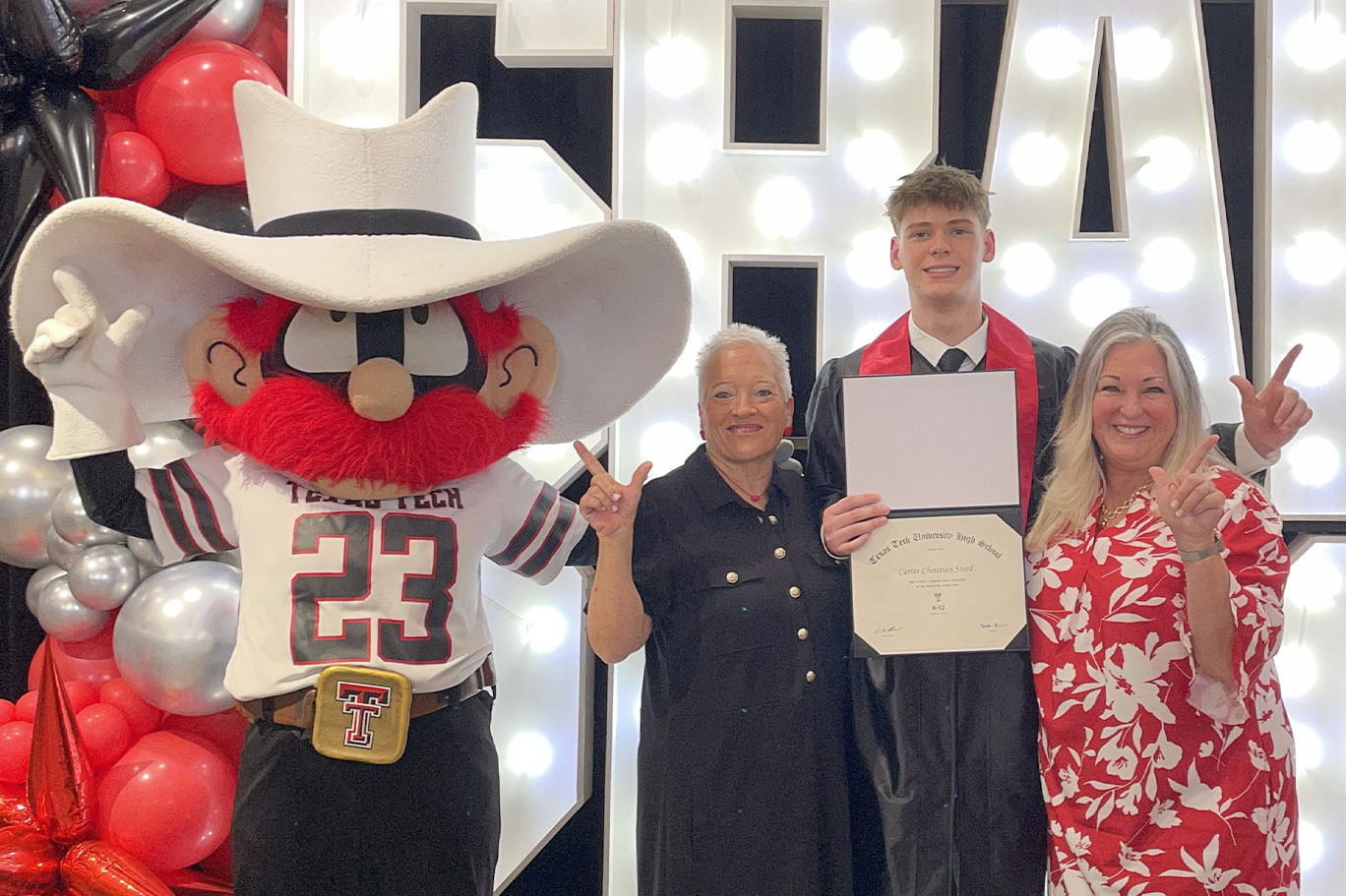 Terri celebrates graduation with Carter Steed, his mom Erin and Raider Red.