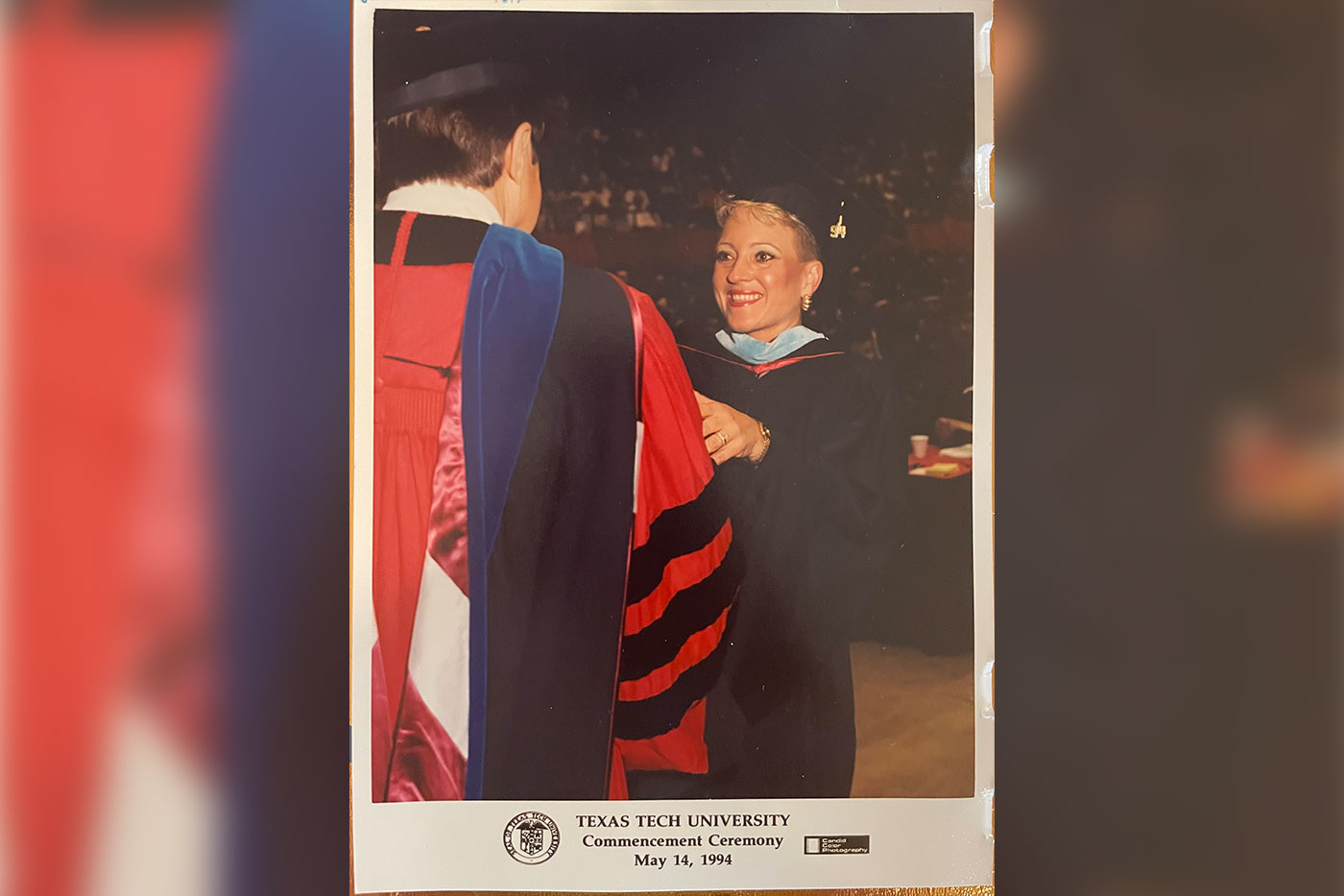 Terri in master's regalia shaking hands with president at graduation