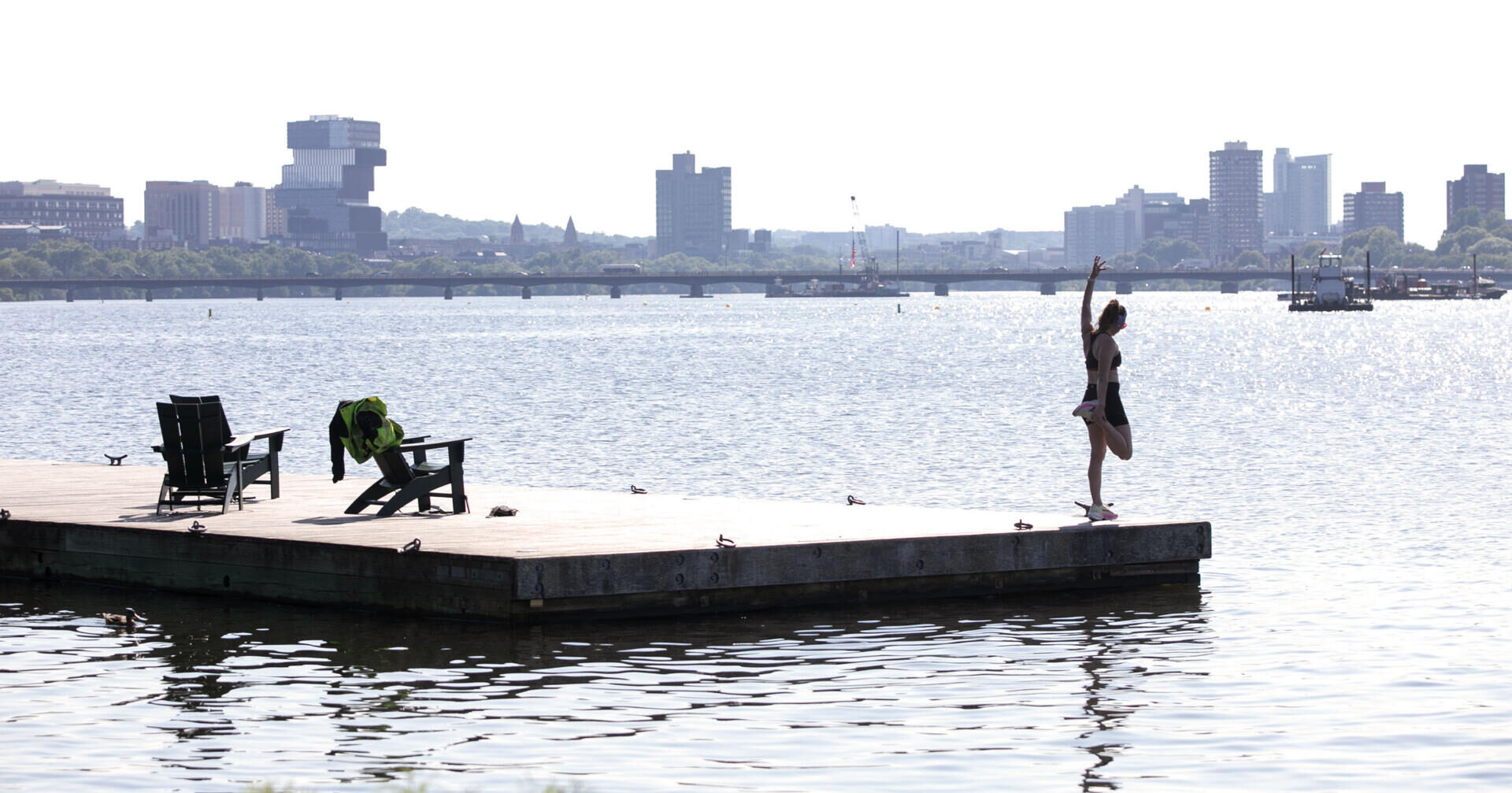 A woman stretches on a dock in the Charles River as the city faces extreme heat on July 1, 2026. (Robin Lubbock/WBUR)