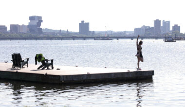 A woman stretches on a dock in the Charles River as the city faces extreme heat on July 1, 2026. (Robin Lubbock/WBUR)