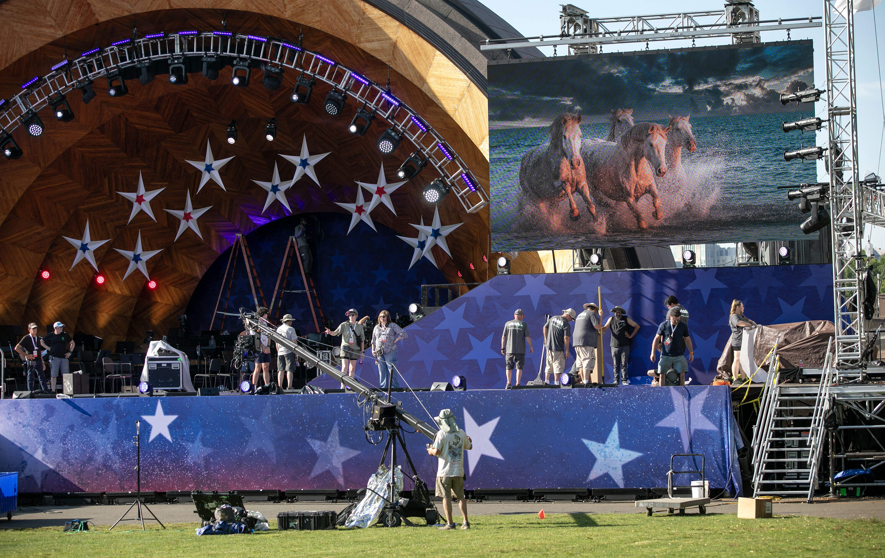 Crews work in the sun on the Hatch Shell stage as July Fourth approaches and the heat in Boston reaches the mid-90s. (Robin Lubbock/WBUR)