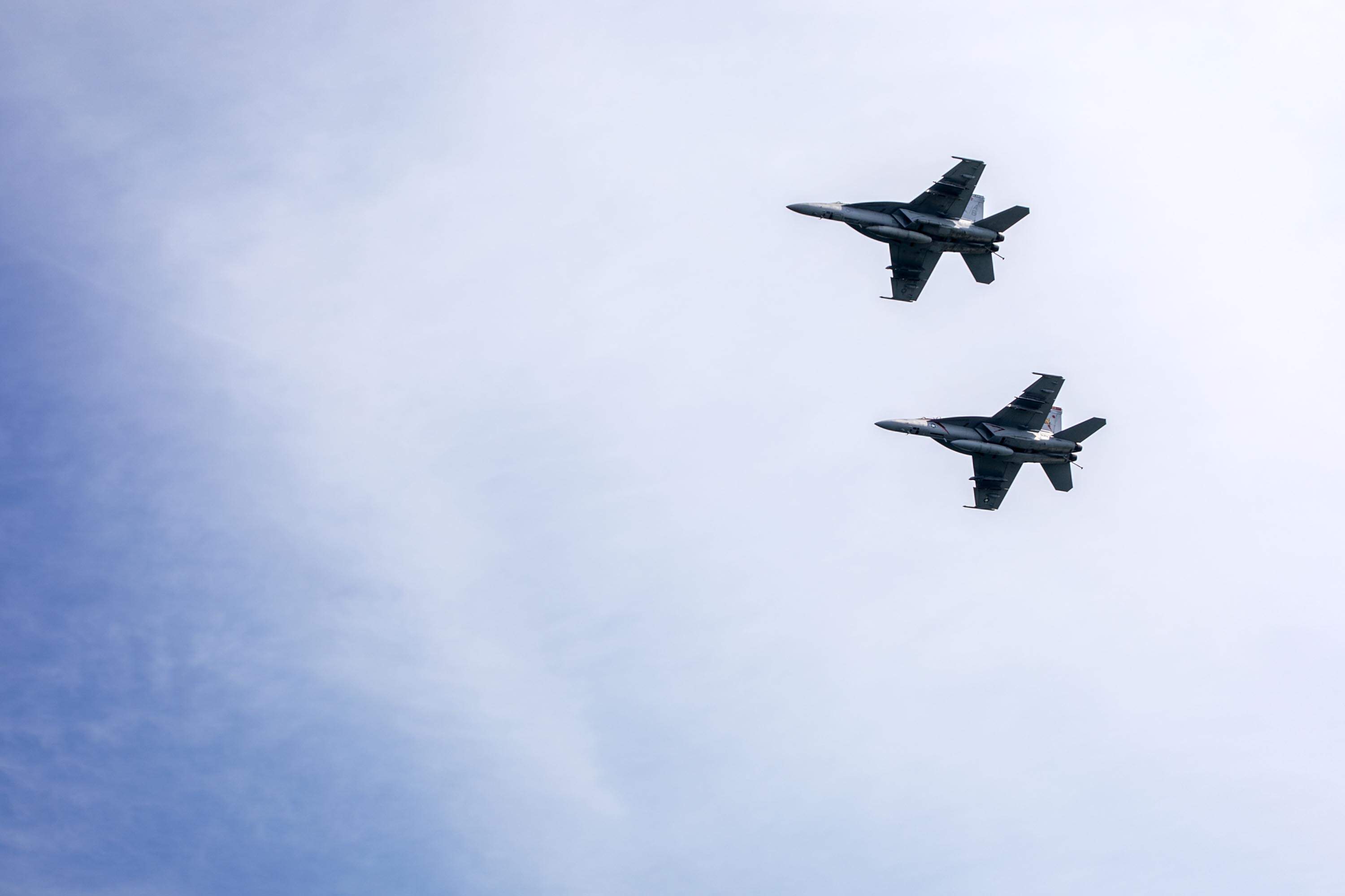 Two Navy F-18s fly over the 2026 Parade of Sail in Boston Harbor. (Robin Lubbock/WBUR)