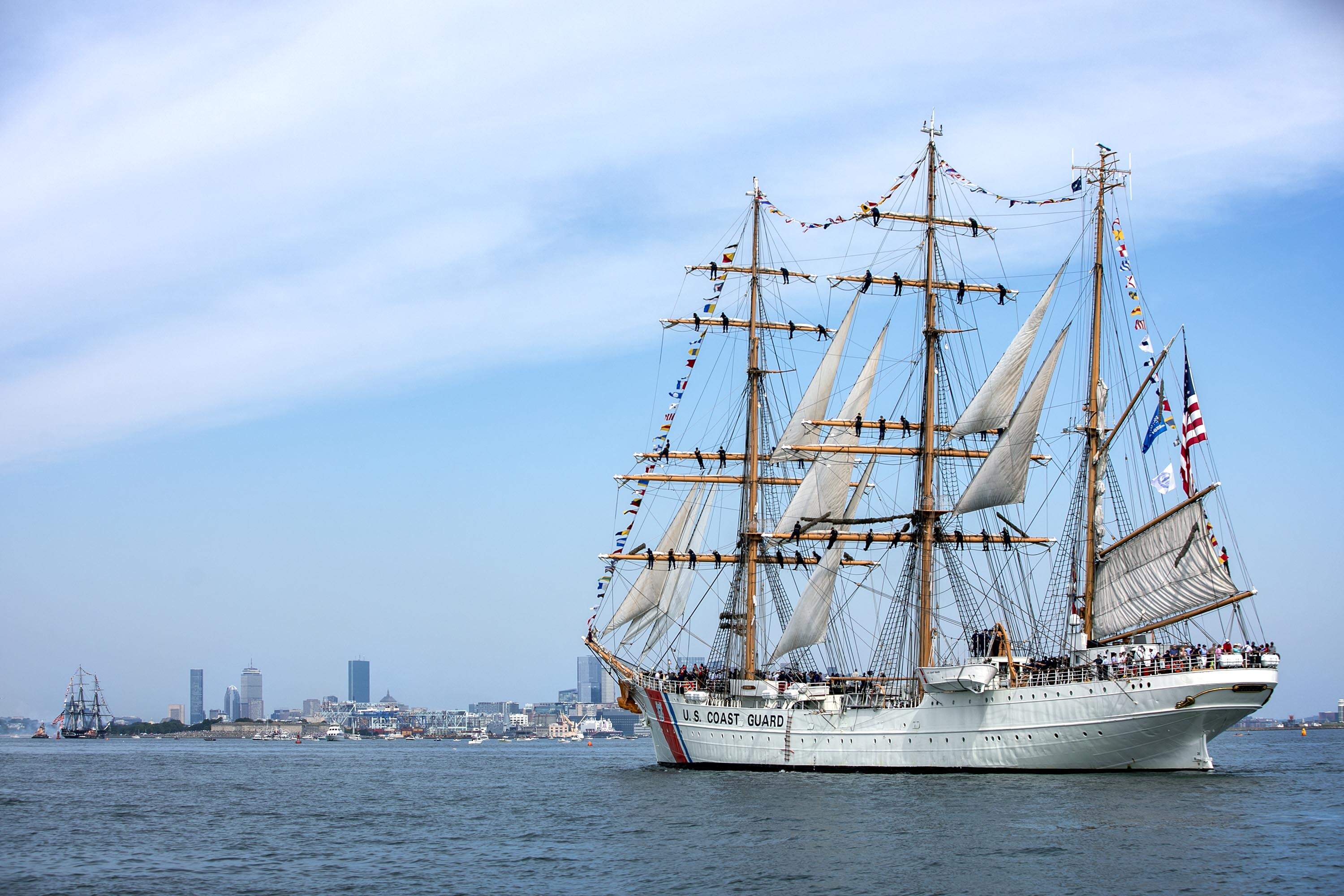 Greeted by the USS Constitution the United States Coast Guard Eagle enters Boston harbor during the 2026 Parade of Sail. (Robin Lubbock/WBUR)