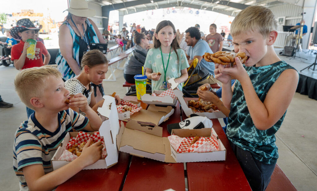Cayden Hyland-Moore (right) chomps down while competing in a funnel cake eating contest at the El Paso County Fair on Sunday, July 12, 2026. The El Paso County Fair will continue in Calhan through July 18. (The Gazette, Jerilee Bennett)