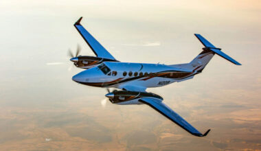 Aircraft in flight above a sunlit landscape.
