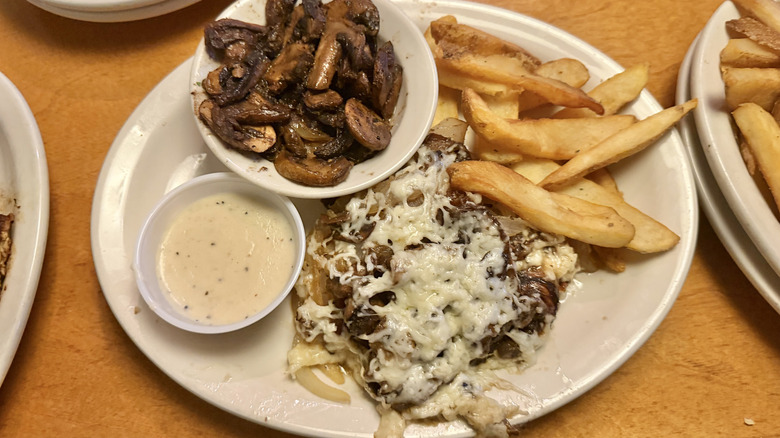 Top view of Smothered Chicken with mushrooms and fries