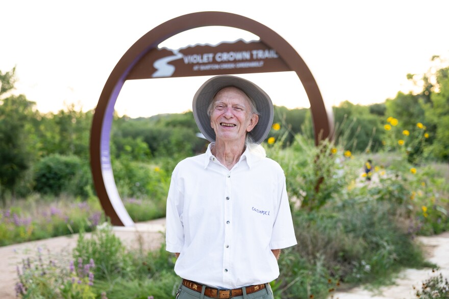 A man poses in front of a trail entrance that is a large circle sculpture. 