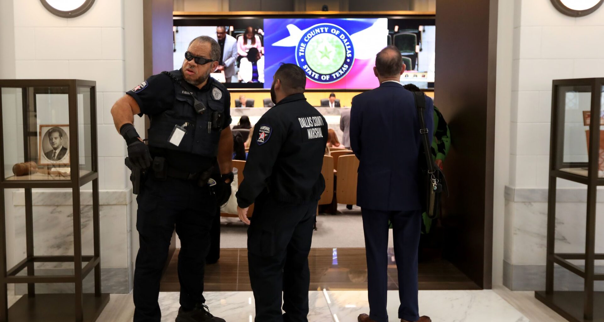 Former Dallas County Fire Marshal assistant chief Zack Masri, center, stands at a Dallas County Commissioners Court meeting April 1, 2025.