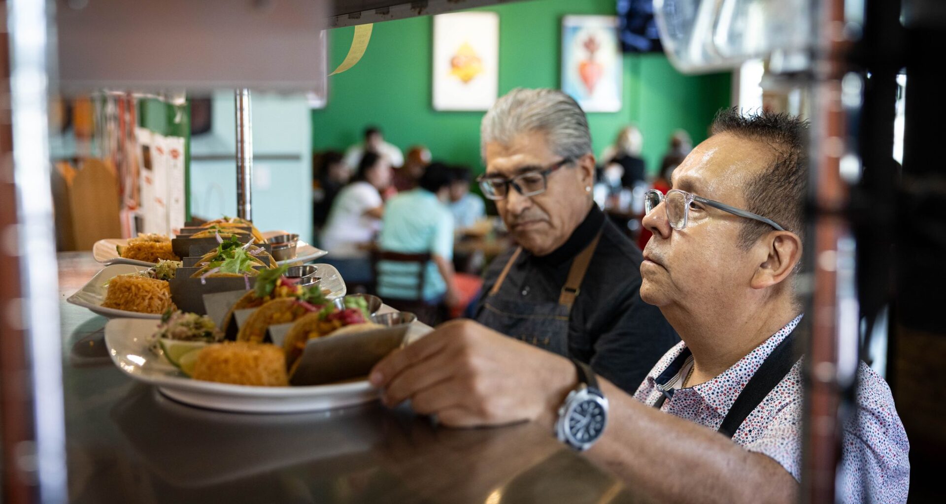 Milagro Tacos Cantina owner, Jesus Carmona, and waiter Angel Ramos serve costumers during lunchtime in Dallas, Friday, June 26, 2026.