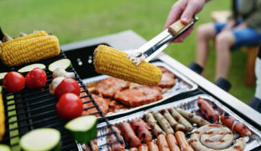 Close-up picture of mixed sausages and meat and vegetables grilling on barbecue. 
