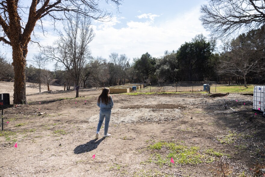 A woman stands looking out on a section of land.